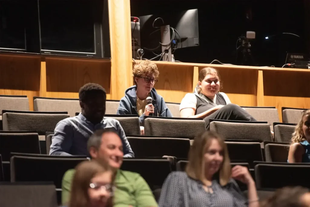 Audience member with a microphone engages in a discussion at a theater event.