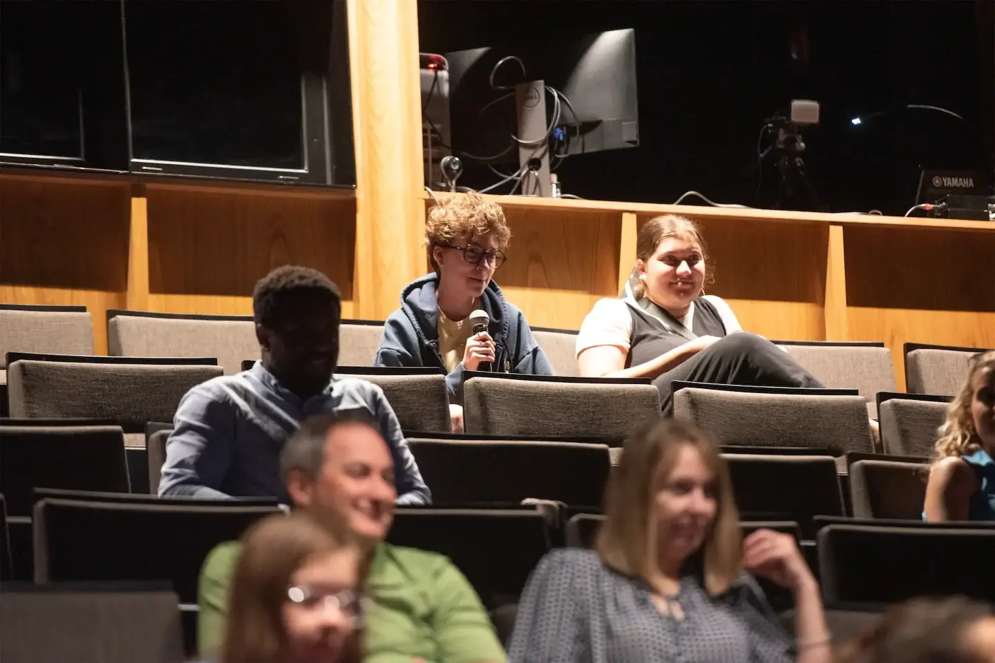 Audience member with a microphone engages in a discussion at a theater event.