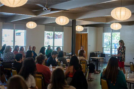 Group of people attending a seminar in a well-lit room with hanging round lights.