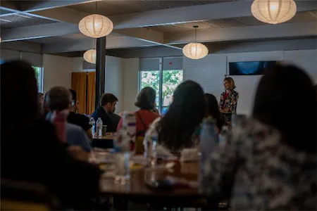 Speaker addressing audience in a conference room with attendees listening attentively.