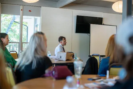 People attending a business presentation in a conference room with a blank screen.