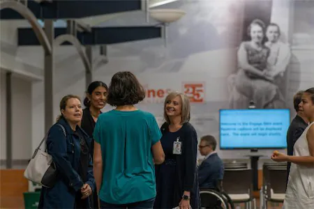 Group of people talking in a museum with a historical photo in the background.