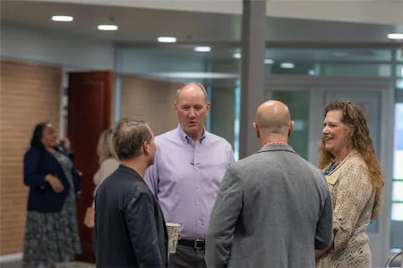 Professionals networking and conversing in a modern office setting, fostering collaboration and business connections.