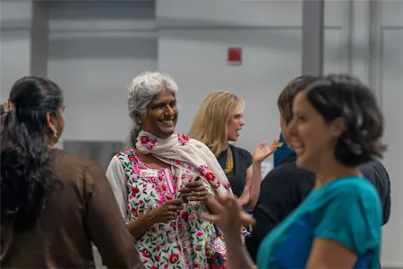 People engaging in lively conversation at a networking event, smiling and sharing ideas indoors.