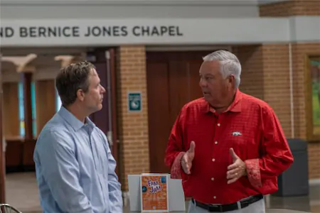 Two men talking near the entrance of a chapel, engaged in conversation.