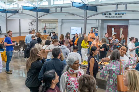 People gathering at a community event in Haas Hall Academy's entrance hall at the Jones Center.