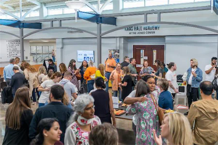 People socializing at an event in the Haas Hall Academy lobby, showcasing a bustling community gathering.