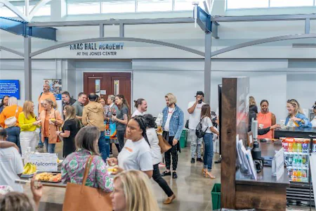 Group of people networking at a school event near the entrance of the Haas Hall Academy at the Jones Center.