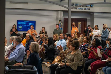 Audience attentively listening during a seminar at Jones Center, with presentations displayed on screen in the background.
