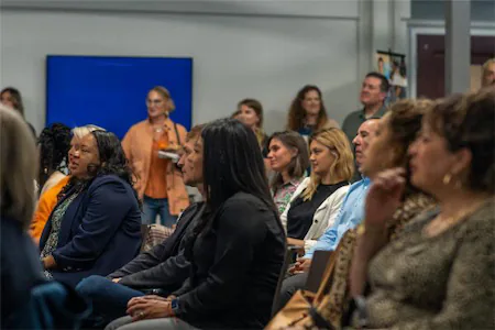 A diverse group attentively watching a presentation in a conference room.