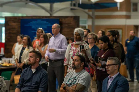 A diverse group of professionals attentively listens at an indoor business event.
