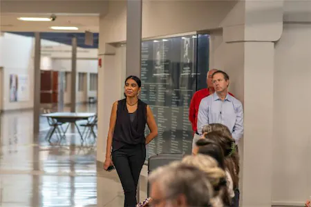 People walking through a hallway during a conference or event, with others seated in the foreground.
