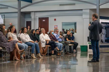 Speaker addressing an attentive audience in a modern conference setting.