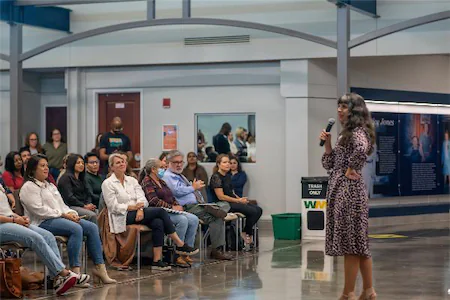 Woman speaking to an engaged audience in a seminar setting, highlighting a dynamic exchange of ideas and inspiration.