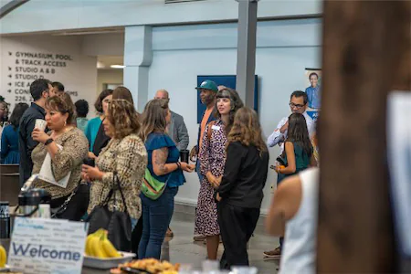 People networking at a business event with food and signage in a spacious venue.