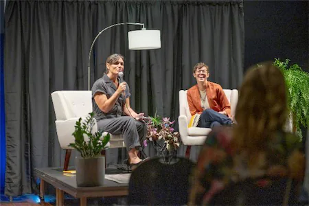 Two speakers engaging with the audience on stage during a lively panel discussion at a conference.