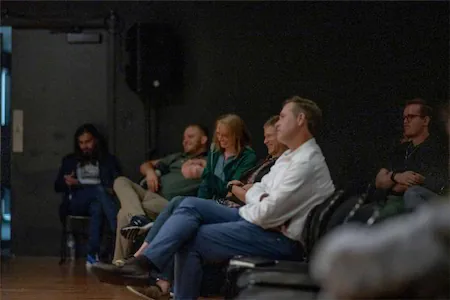 Audience attentively watching a presentation in a dimly lit room.