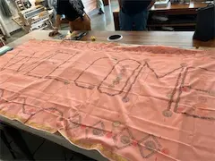 Large Welcome banner on a pink cloth spread across a table in a workshop setting.