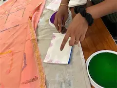 Person demonstrating block printing on fabric with vibrant colors and patterns. Craft technique, close-up.