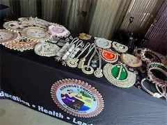 Collection of traditional handcrafted necklaces displayed on a table with organizational logo and text.