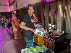 Smiling vendor at a colorful market stall showcasing handcrafted products indoors.