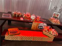 Baked goods display on a wooden table featuring Rockin' Baker products in various packaging with promotional materials.