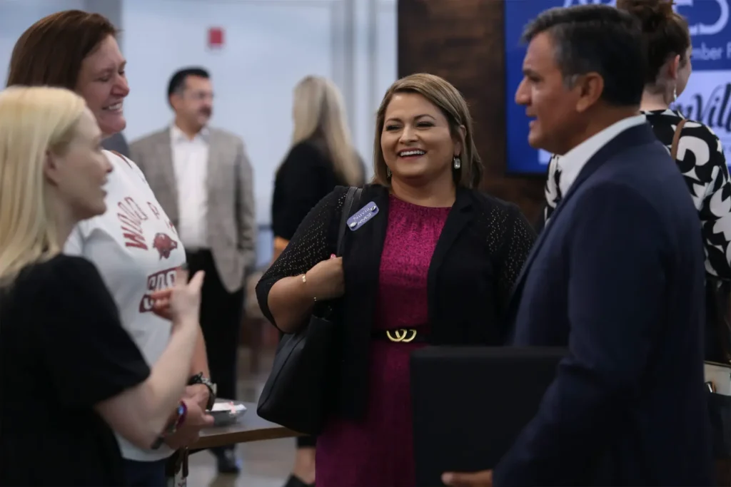 People networking at a business event, smiling and engaging in conversation.