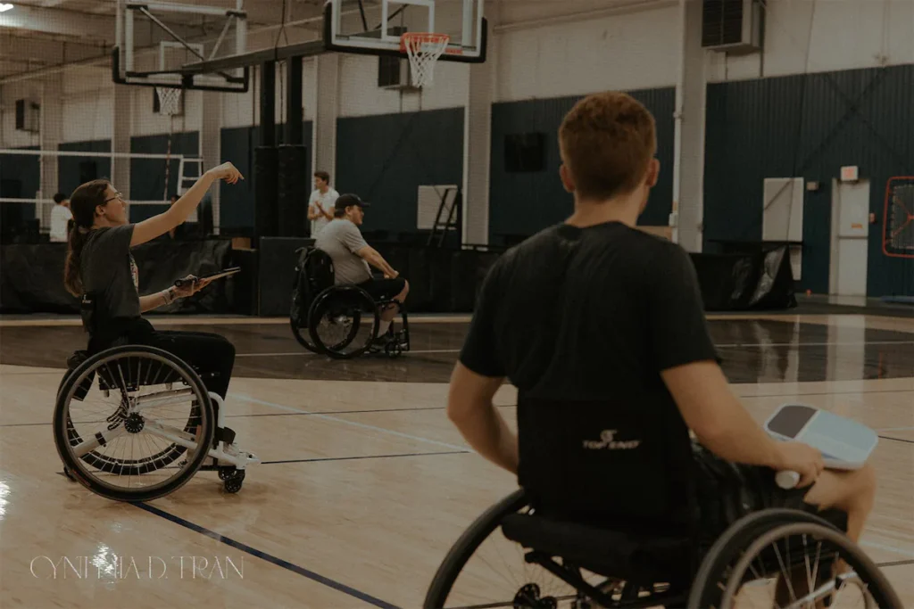 Wheelchair basketball practice in a gym, featuring players actively engaged on the court.