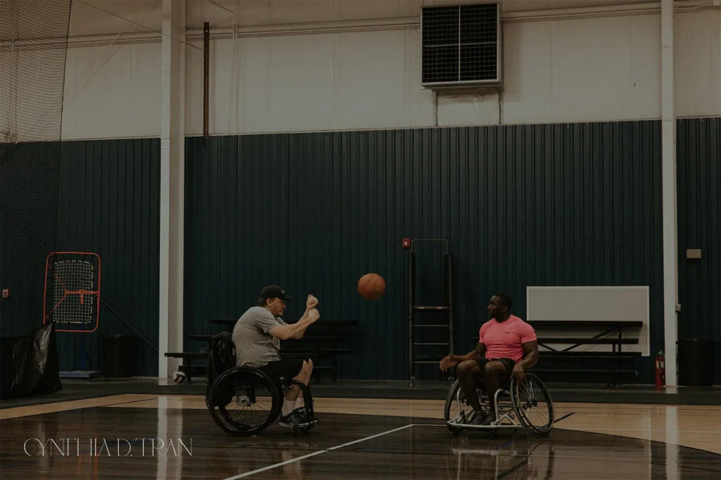 Wheelchair basketball players passing ball in indoor court.
